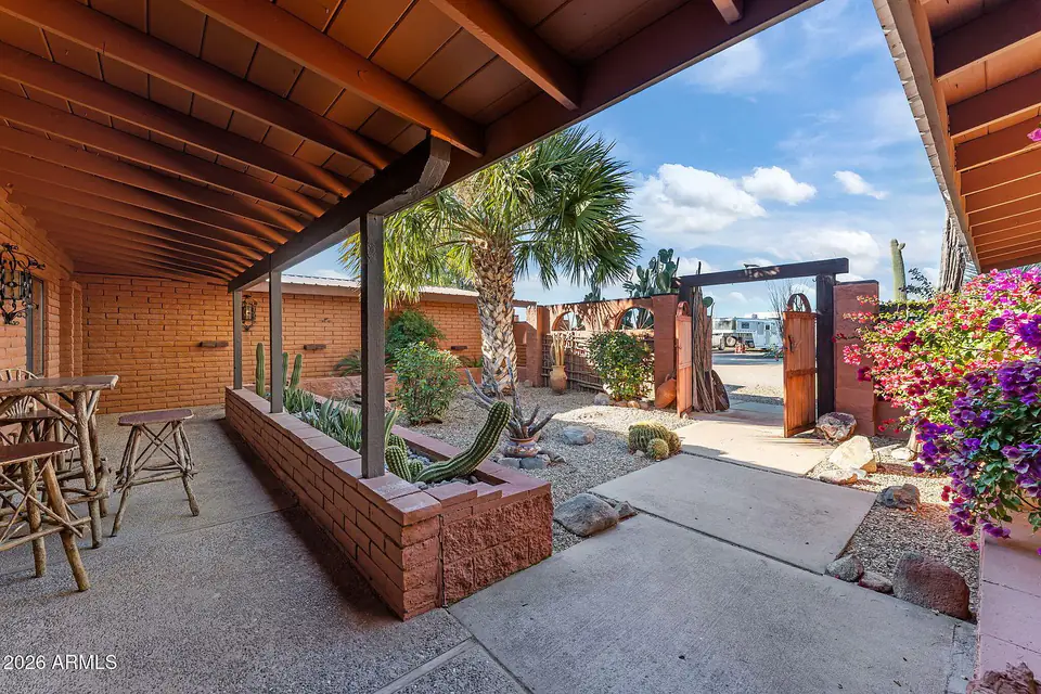 Covered entry courtyard with brick planters, palms, and bougainvillea